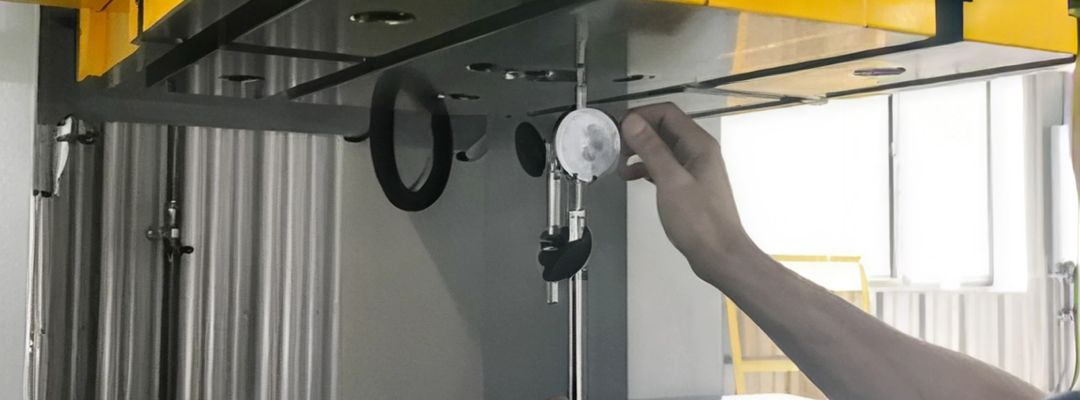 Technician adjusting a gauge on an overhead crane's overload protection system.